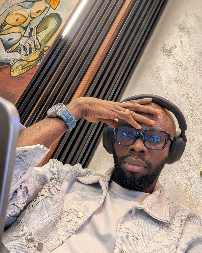 Sky at his laptop wearing headphones and glasses, hand on his forehead